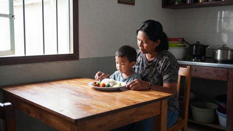 Ilustrasi ibu mendampingi anak makan di rumah